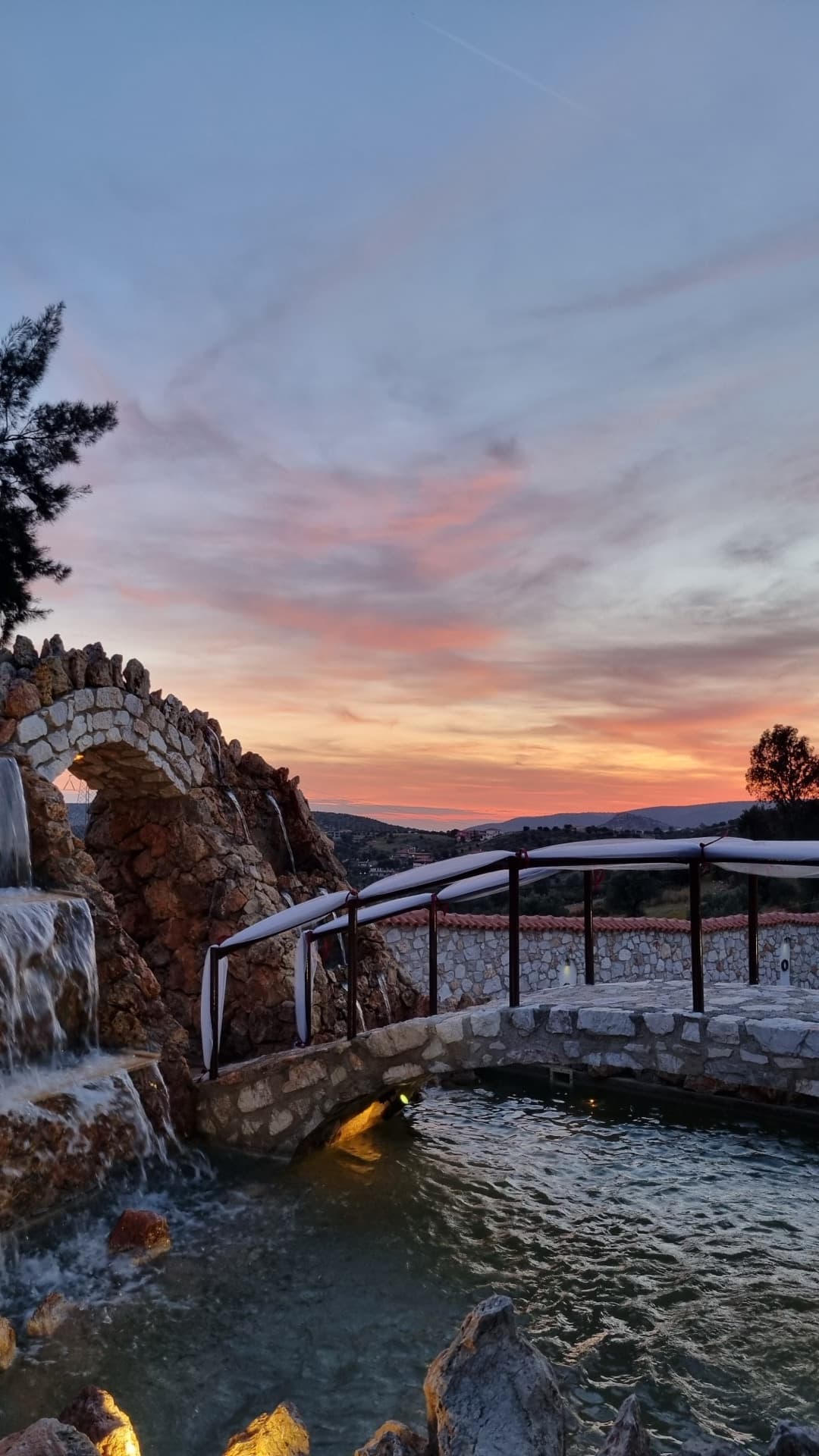 Sunset over stone bridge and waterfall at reception venue Attica