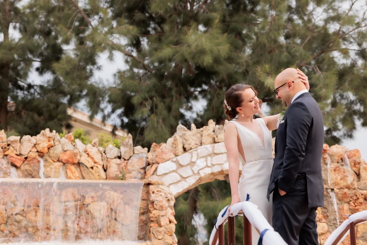 Newlywed couple on stone bridge with waterfall — wedding reception Ktima Filokalis Koropi